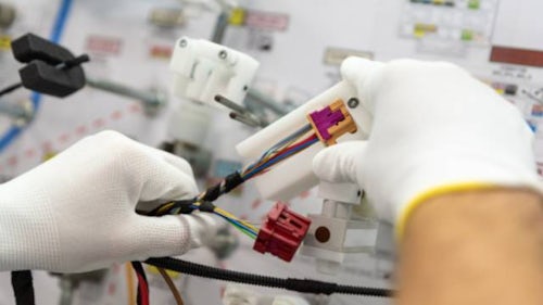 Hand holding a wiring harness in a wiring harness manufacturing plant